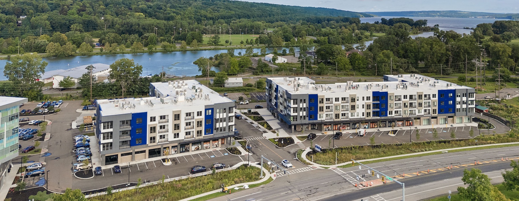 two buildings with parking lots by a body of water
